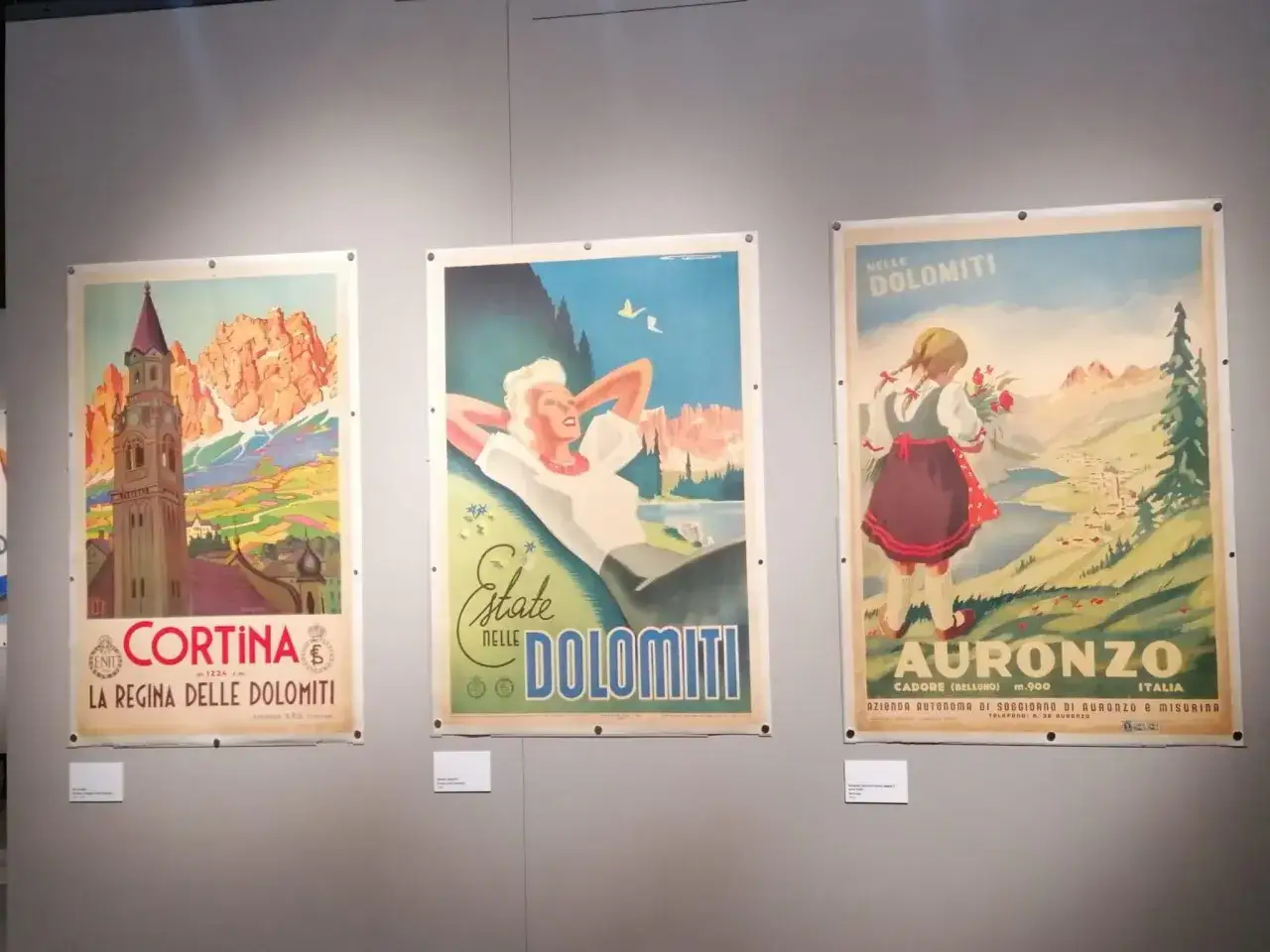 Tre manifesti vintage di una collezione salce promuovono le Dolomiti: Cortina, una donna rilassata e una bambina ad Auronzo.
