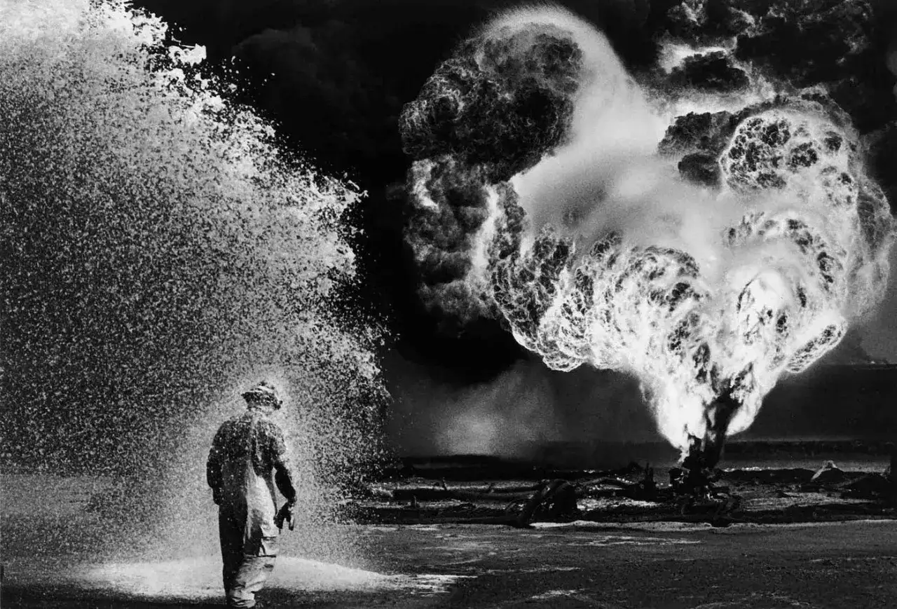 Un uomo in tuta protettiva affronta un'esplosione fiammeggiante, un'immagine che cattura la potenza della natura e la maestria del miglior fotografo al mondo.