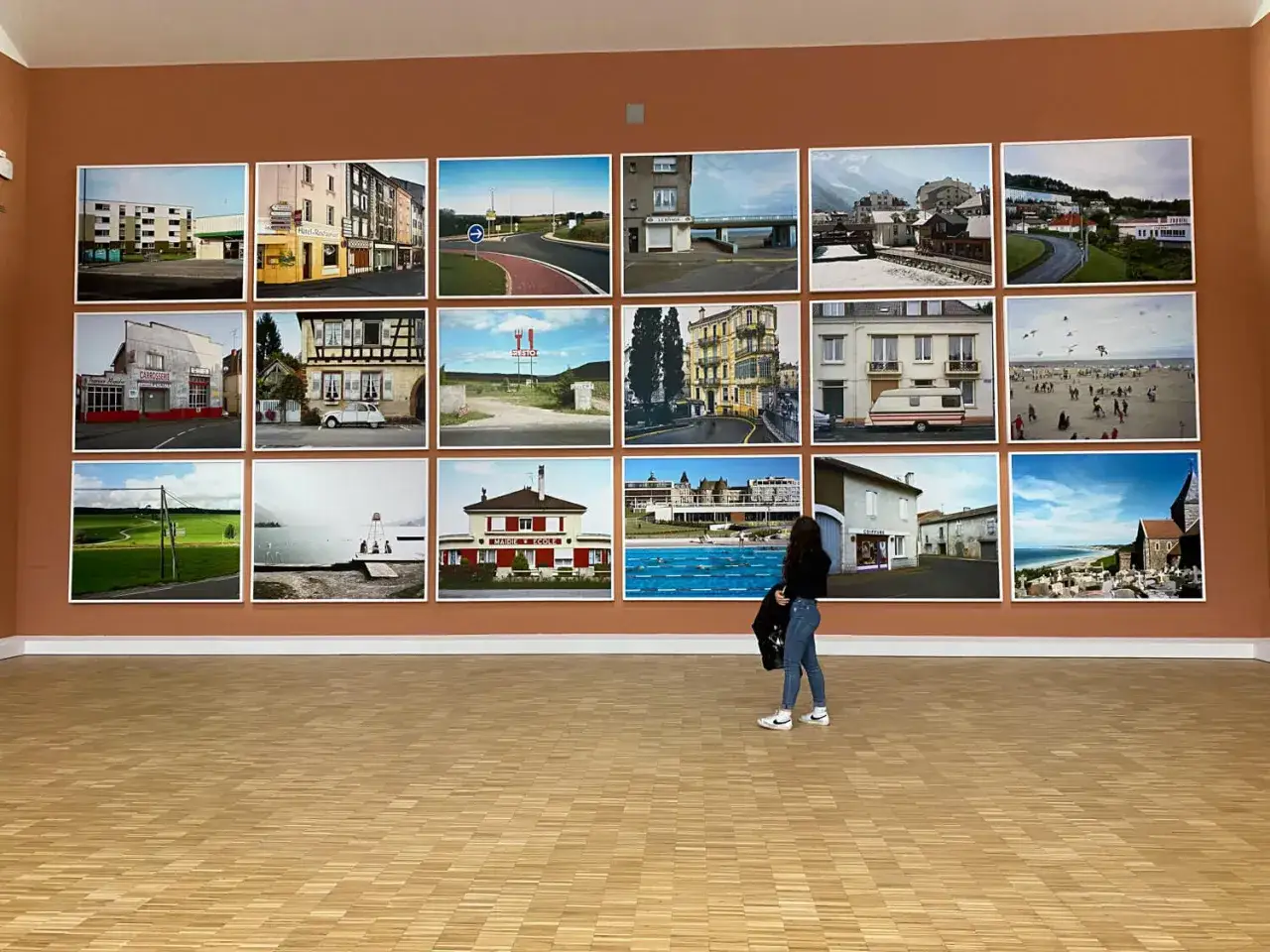 Mostra di fotografie di Raymond Depardon: paesaggi urbani e rurali francesi, una donna osserva le opere.