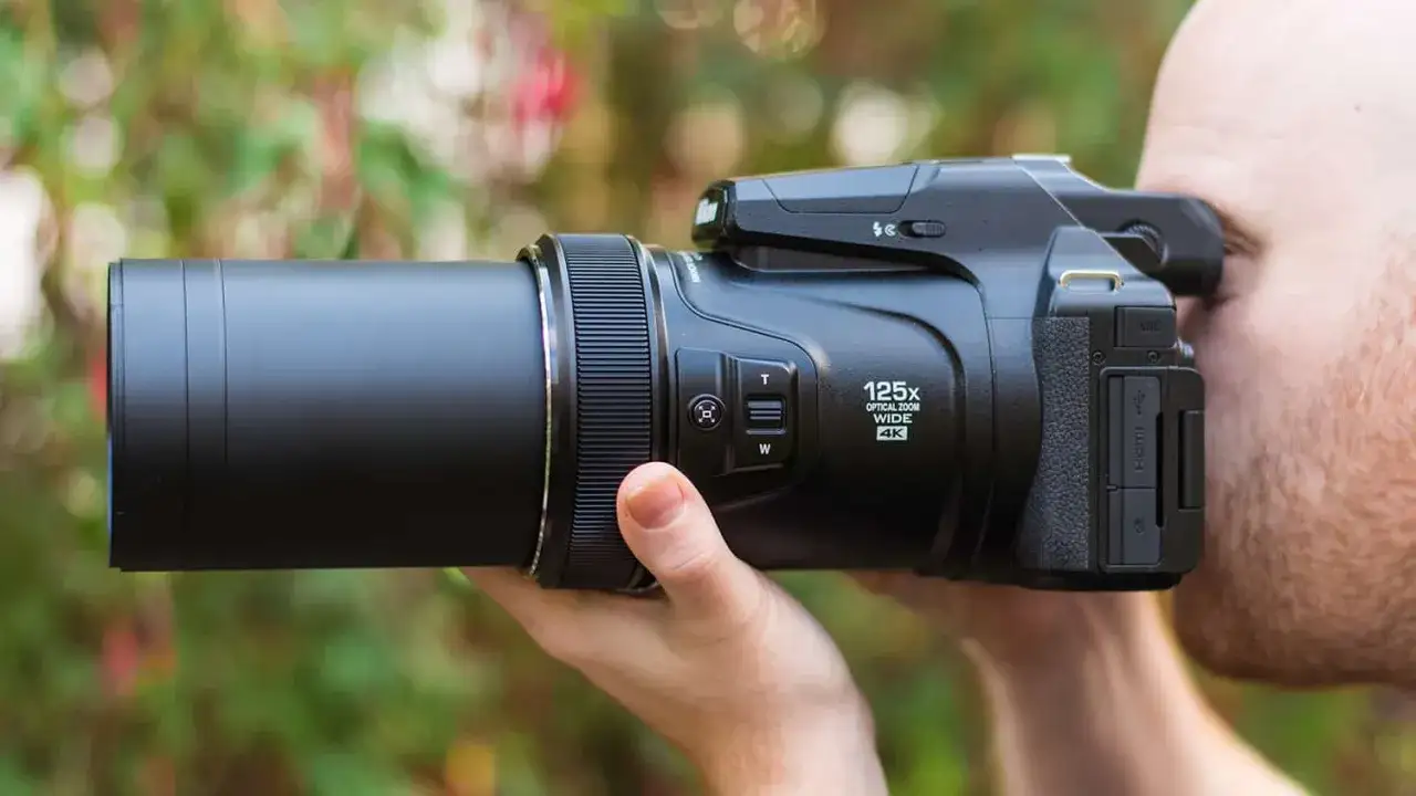 Un uomo usa una fotocamera bridge con zoom 125x. Scopri cosa sono le fotocamere bridge e le loro potenzialità.