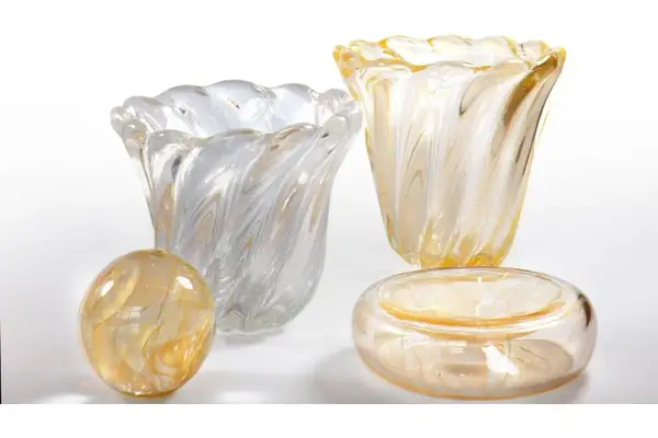 Vasi e oggetti decorativi in vetro soffiato, con fili dorati e bianchi, che evocano la maestria di Seguso Vetri d'Arte.