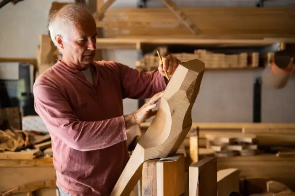 Saverio Pastor, scultore del legno, con matita e mani esperte definisce le forme di un'opera in lavorazione.